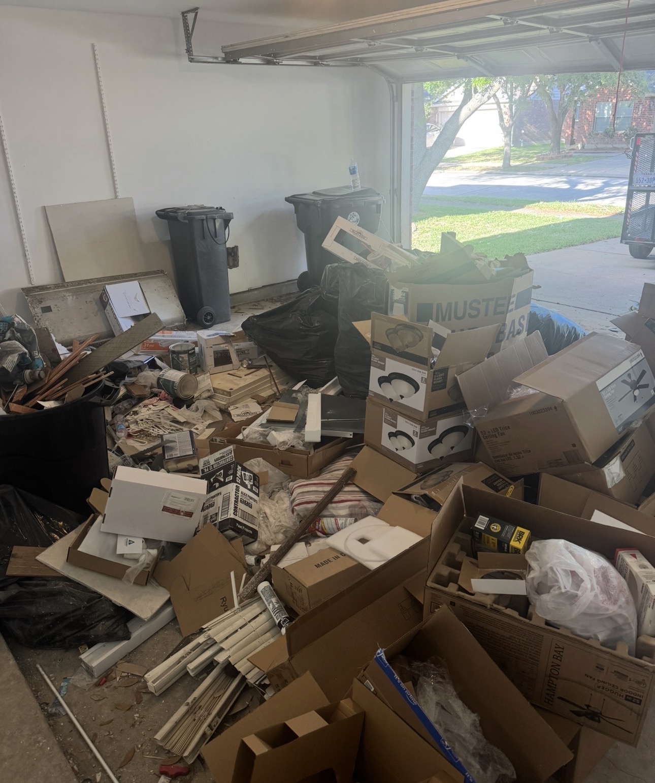Garage filled with remodeling debris, cardboard boxes and construction materials before a contractor haul-off in Houston