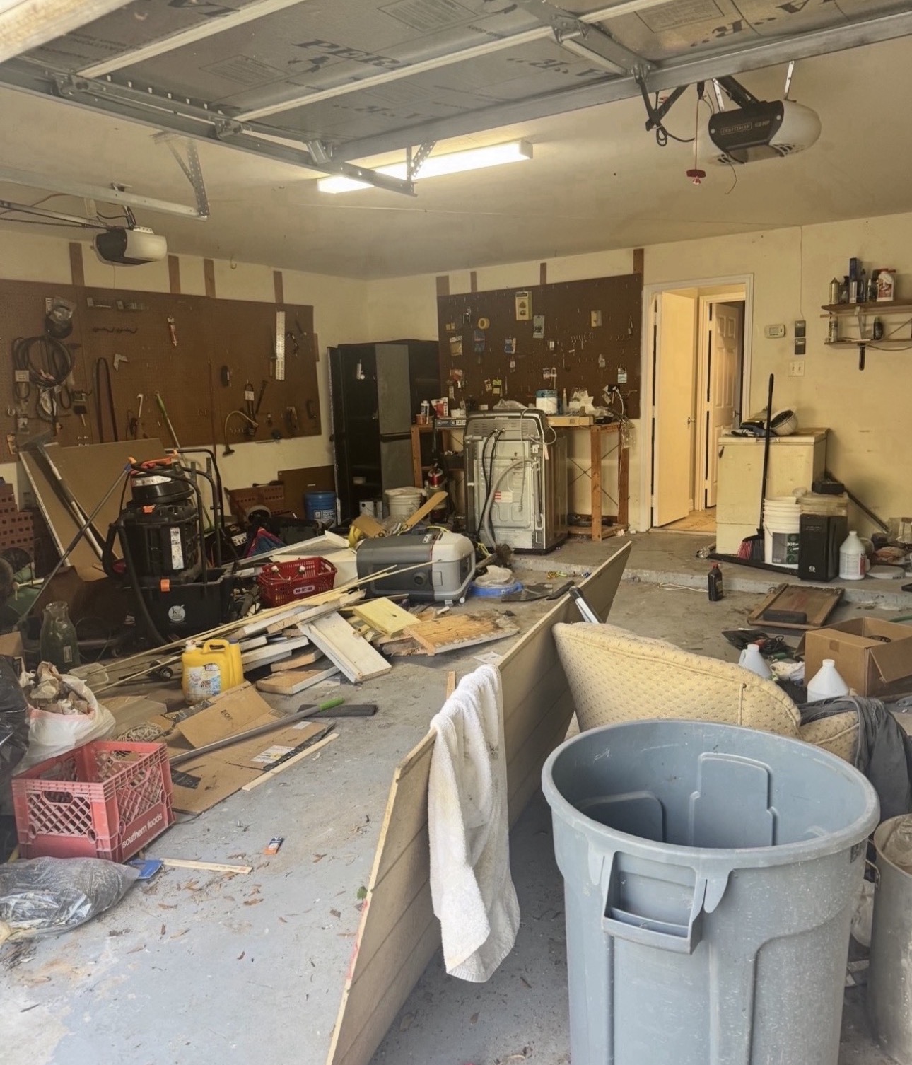 Garage packed with lumber, shop vacuums, buckets and household clutter before cleanout